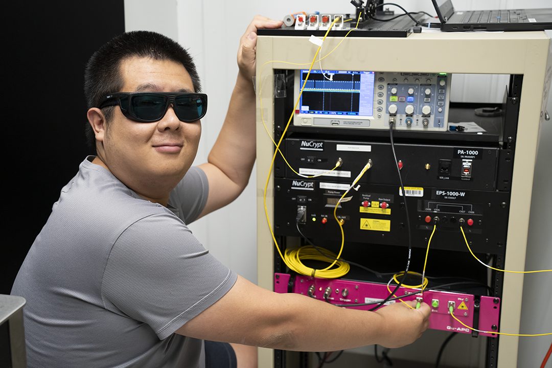 NIST physicist Yicheng Shi, lead author of the study, working at the optical bench used to generate and measure the entangled photon pairs sent across 62 km of commercial fiber between Gaithersburg and College Park, Maryland.